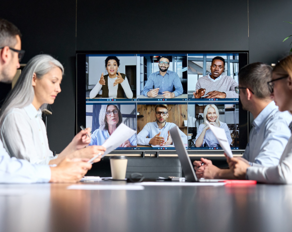 Medewerkers in een moderne hybride vergaderruimte die met één druk op de knop een meeting starten via Unite.